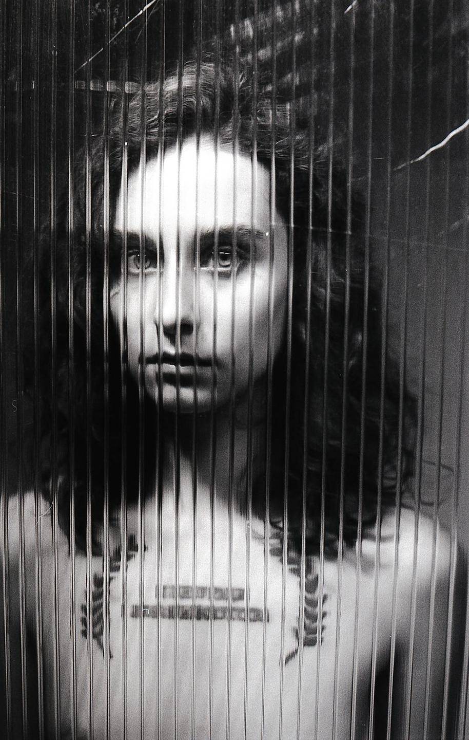 A woman with long hair is visible through a textured glass panel.