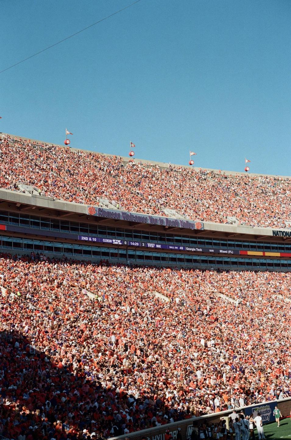 A large crowd of people fills a stadium during a college football game.