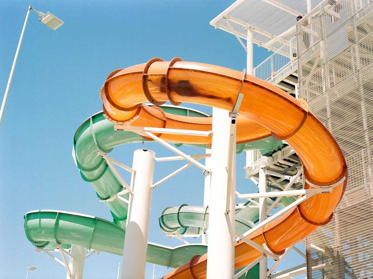 Two colorful water slides twist and turn against a clear blue sky.