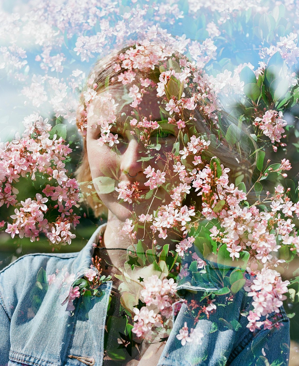 A woman's face is visible through a double exposure with pink blossoms.