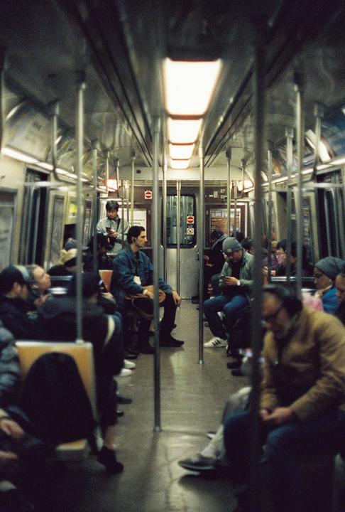 People are sitting and standing inside a subway car.