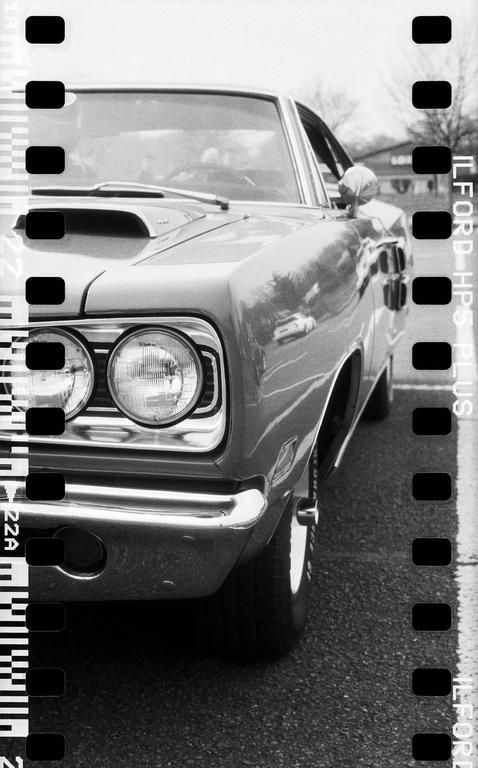 A classic car is parked on an asphalt surface, viewed from the front quarter panel.