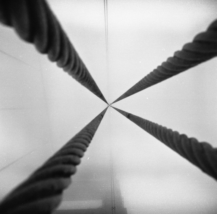 Four thick cables converge towards a vanishing point in the distance, disappearing into a hazy sky.