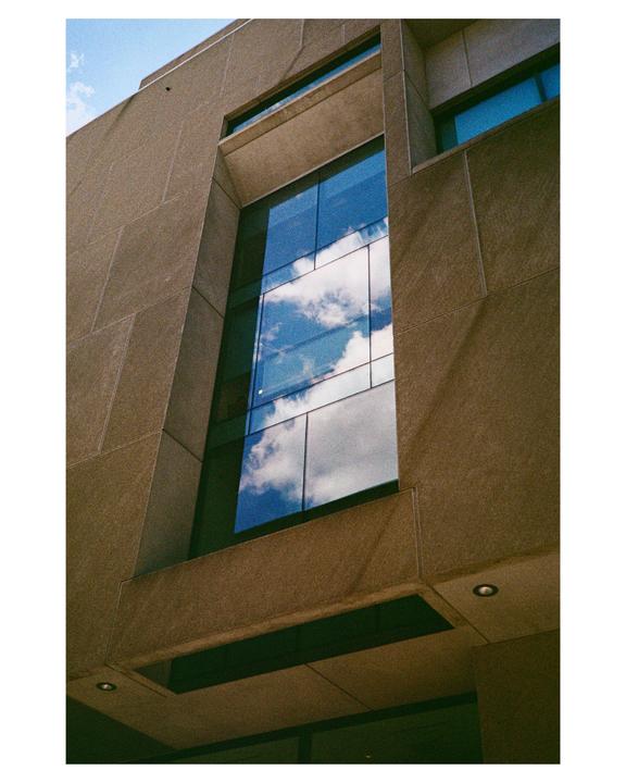 Clouds are reflected in the windows of a modern building.