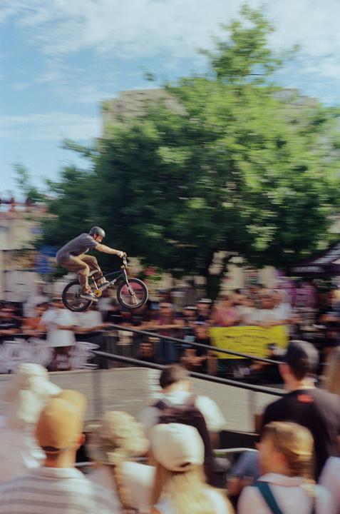 A man on a BMX bike is captured mid-air above a crowd of spectators.