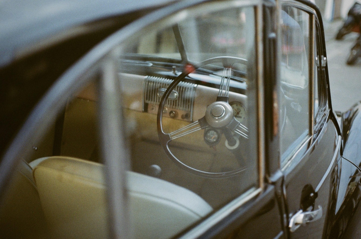 The interior of a vintage car with a steering wheel and dashboard is visible through the window.