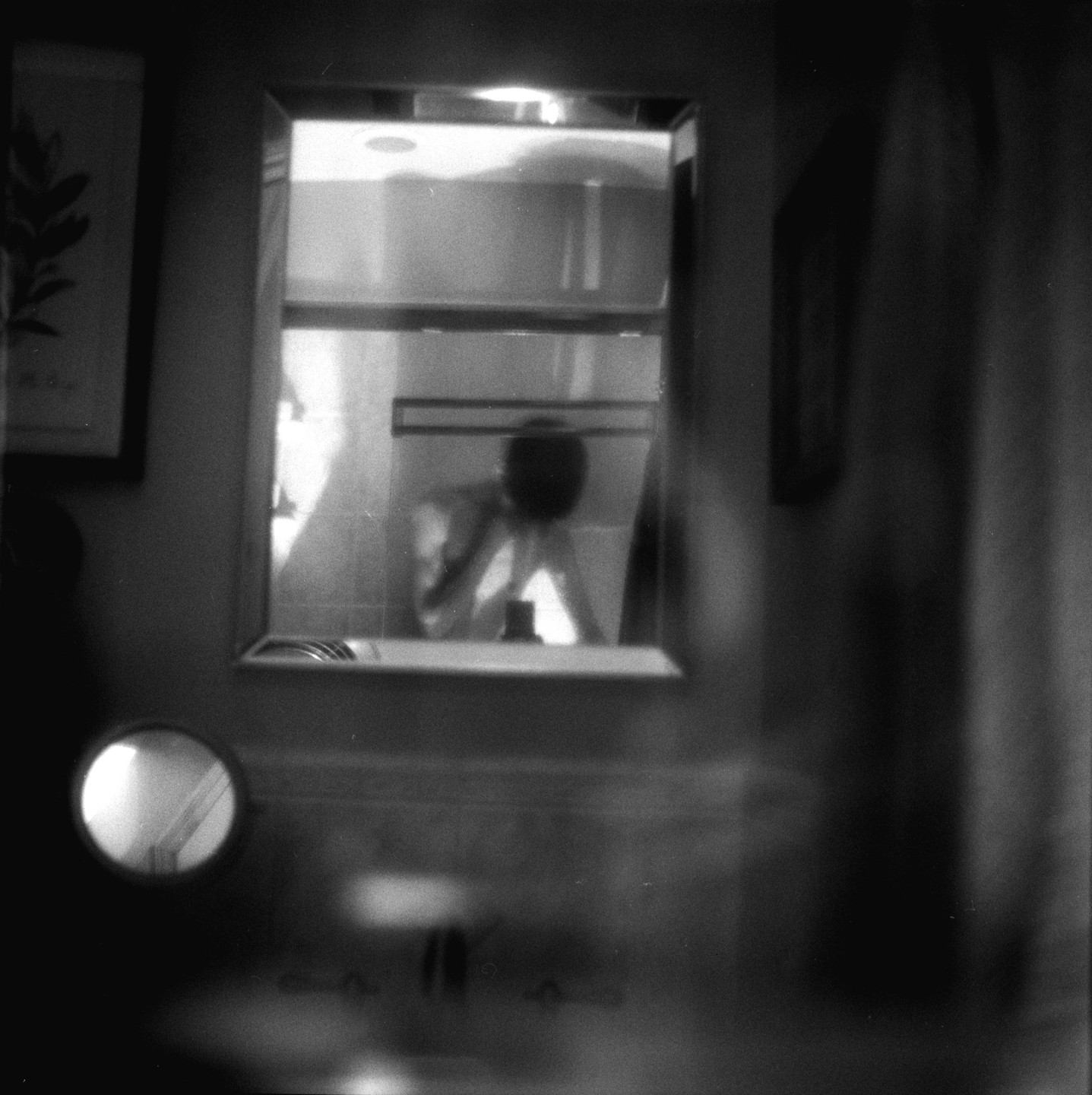 A blurry self-portrait shows a person leaning over a sink, reflected in a mirror.