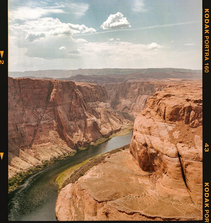 A river winds through a deep canyon under a cloudy sky.