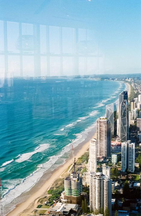 An aerial view shows a city skyline along a coastline with waves crashing on the beach.