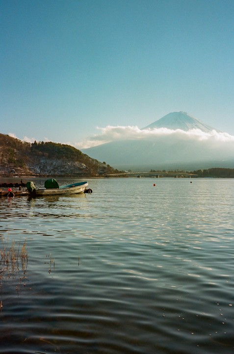 A boat is docked on a lake with a snow-capped mountain in the background.