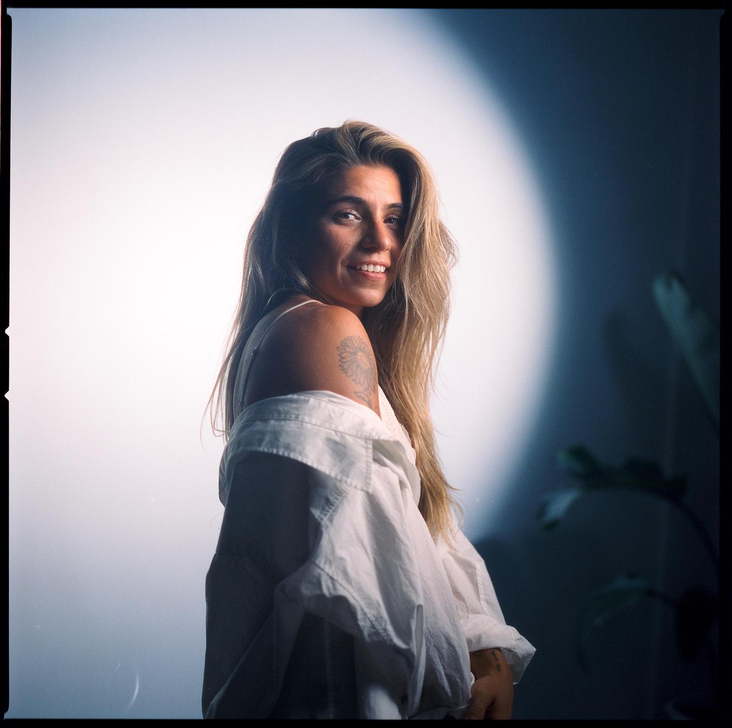 A woman with long hair and a white shirt smiles at the viewer.