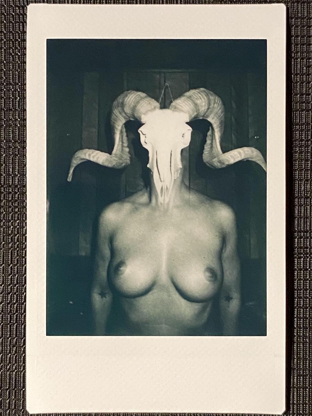 A woman with a ram skull covering her face is visible in a monochrome self-portrait.