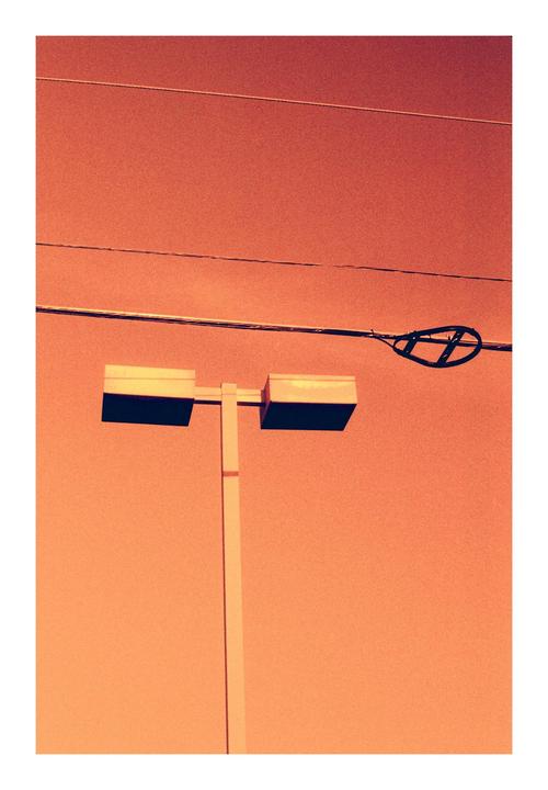 A street light and power lines are visible against an orange sky.