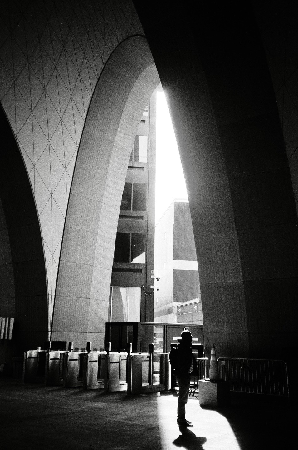A person stands in a shaft of light under large concrete arches at Boston South Station.