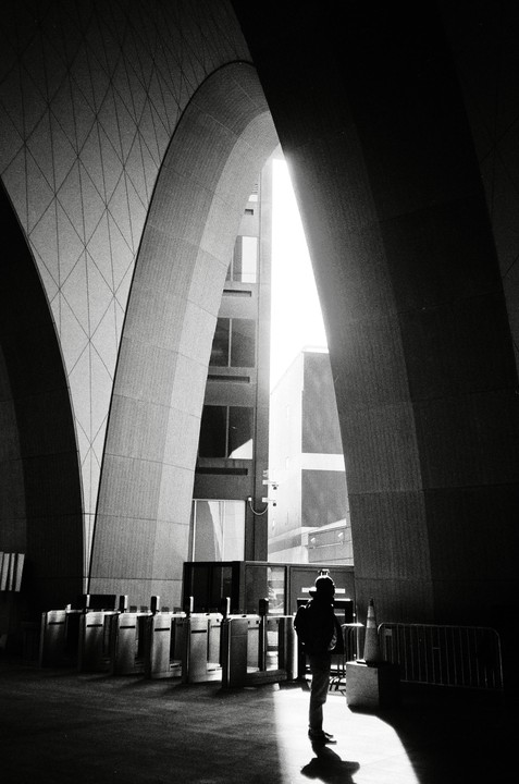 A person stands in a shaft of light under large concrete arches at Boston South Station.
