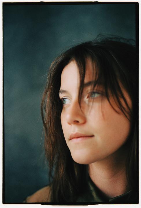 A woman with long hair looks to the right of the frame.