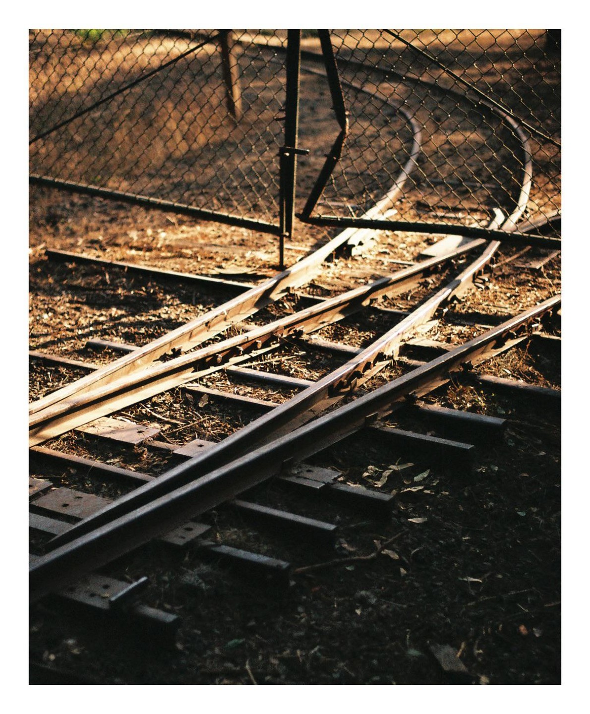 Miniature railroad tracks are visible through a chain link fence.