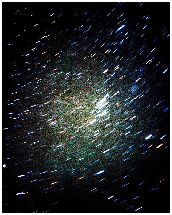 A long exposure photograph captures the movement of stars across the night sky, creating star trails.