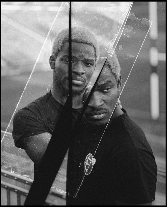 A man with light-colored hair is shown in a double exposure with a collage of negatives.