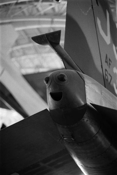A black and white close-up shows the tail of an airplane with a smiling face painted on it.