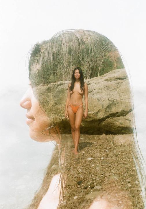 A double exposure shows a woman in profile overlaid with a full-body shot of the same woman standing on a rocky beach.