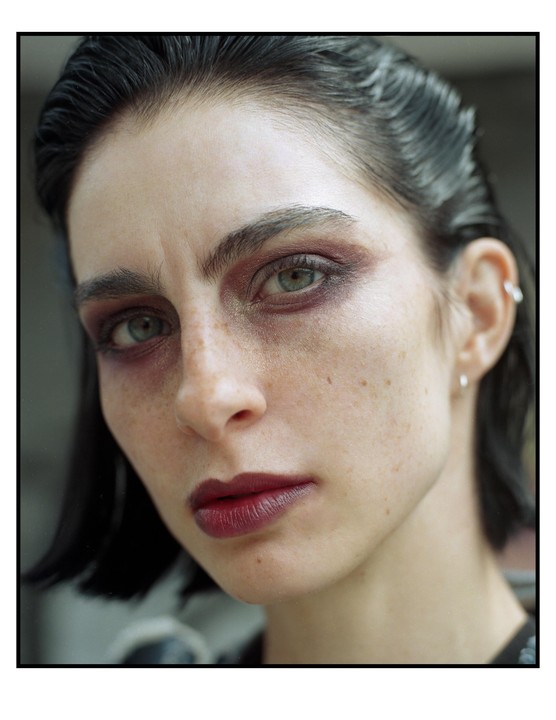 A woman with dark hair and dramatic eye makeup looks directly at the viewer.