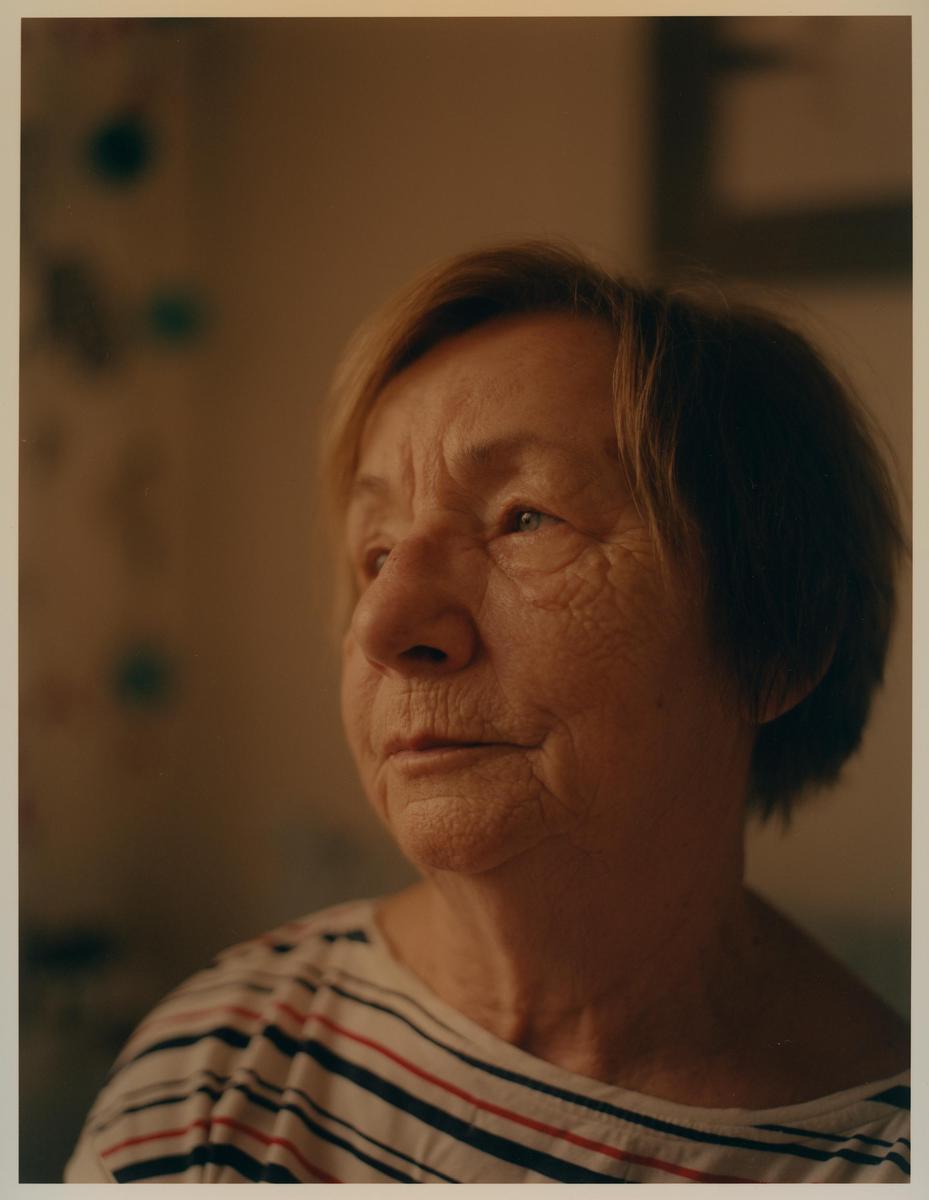 A woman with short hair and a striped shirt looks to the side.
