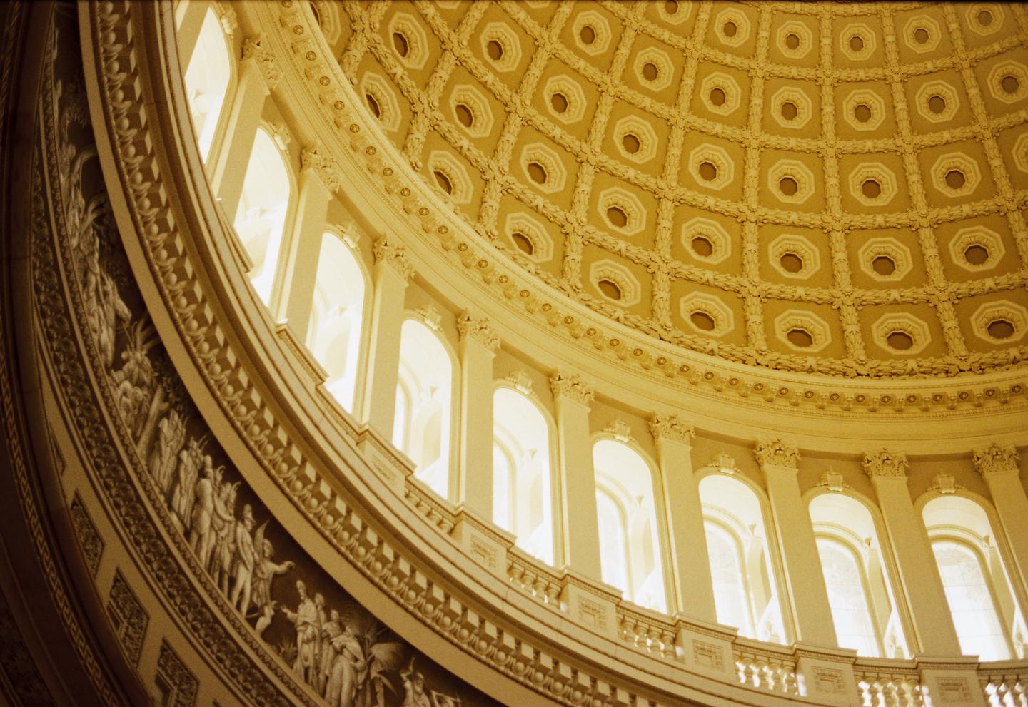 The ornate interior of a large dome features a coffered ceiling and a frieze with sculpted figures.