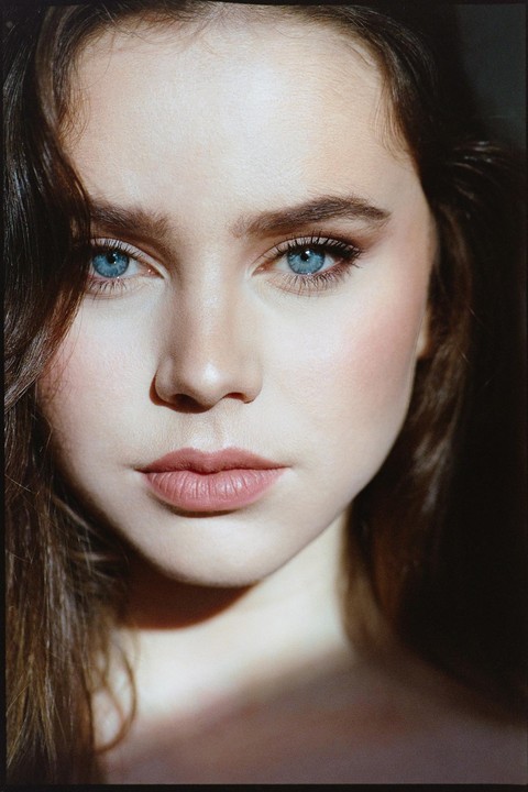 A woman with blue eyes and brown hair looks directly at the viewer.