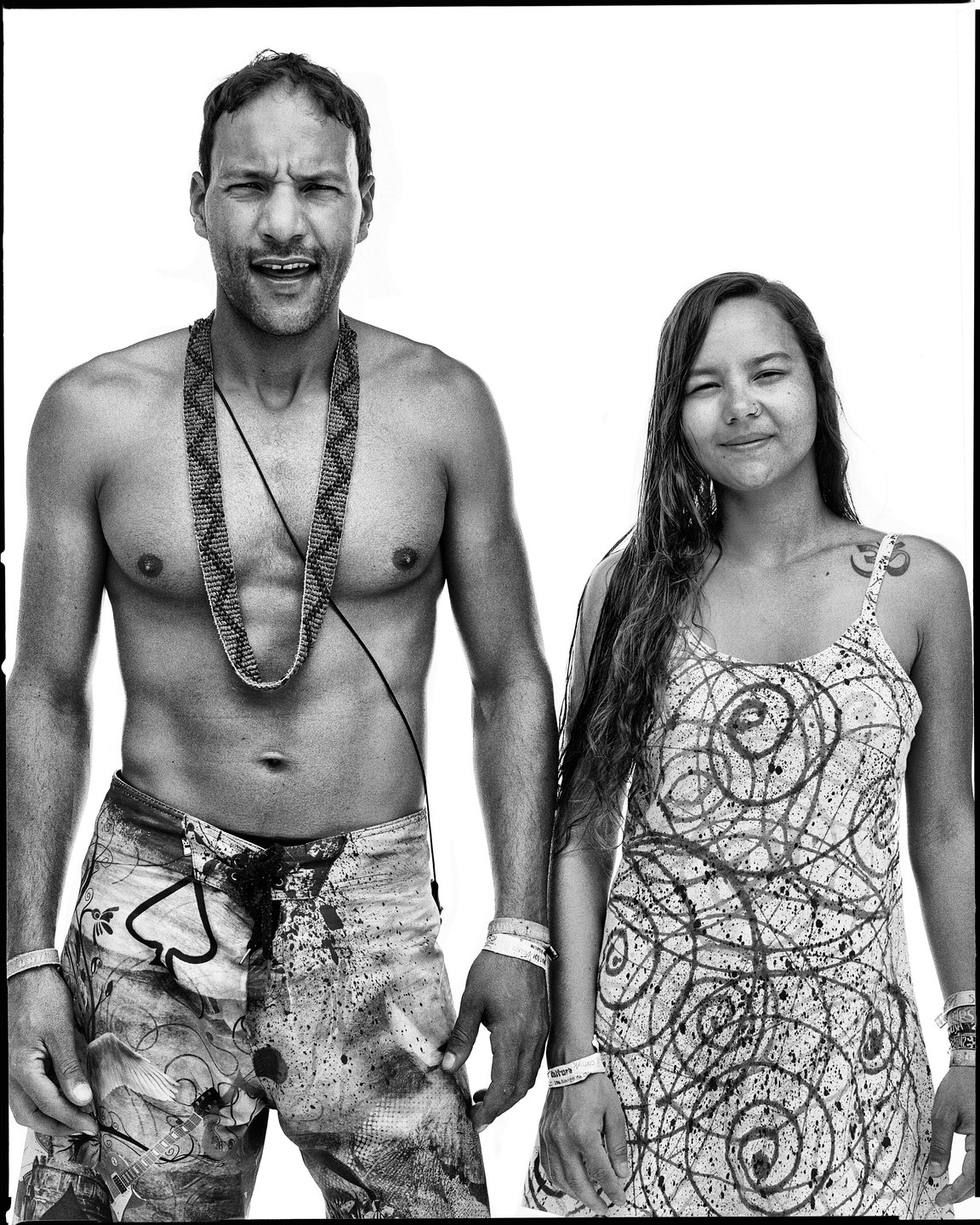 A man and a woman stand side by side, both wearing patterned clothing and wristbands.