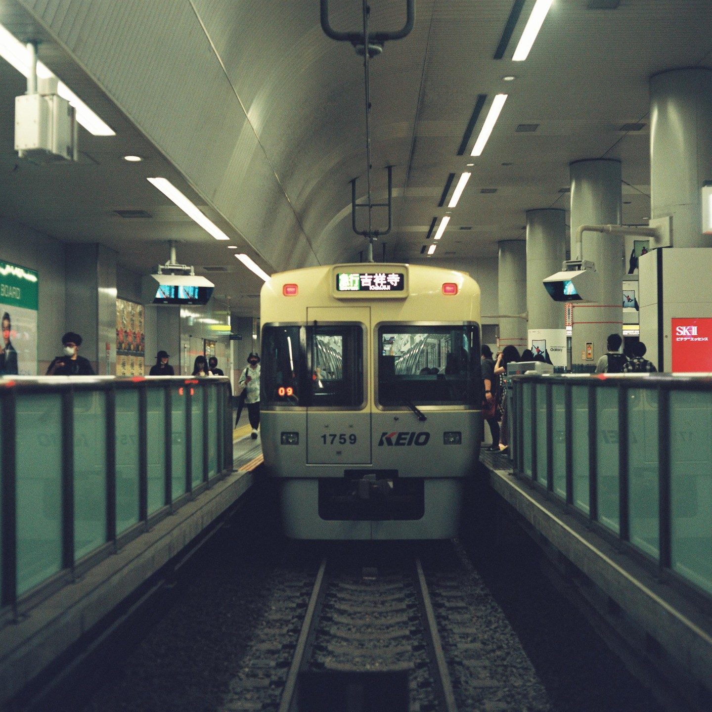 A train is stopped at a subway station with people waiting on the platform.