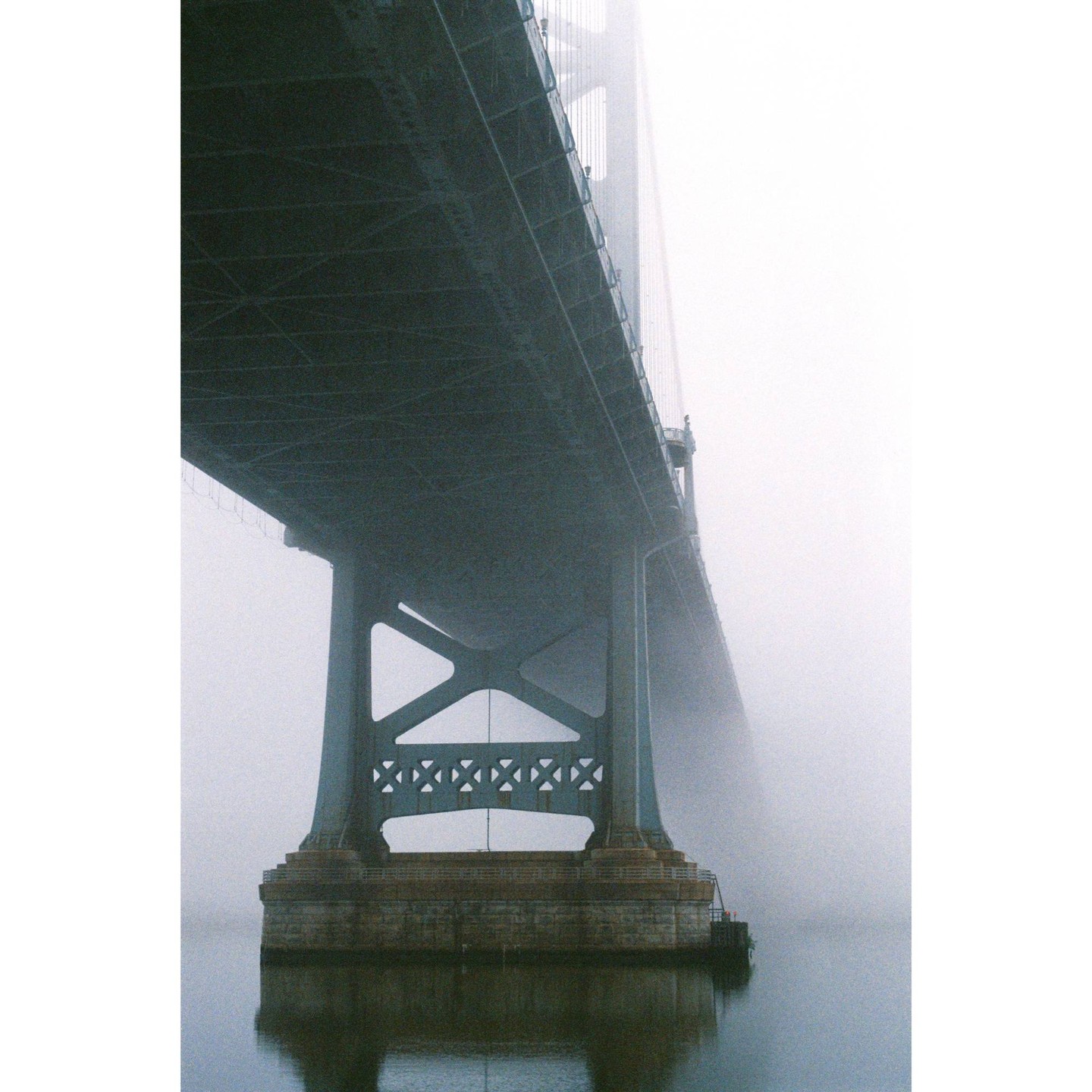 The Benjamin Franklin Bridge is seen from below, partially obscured by fog.