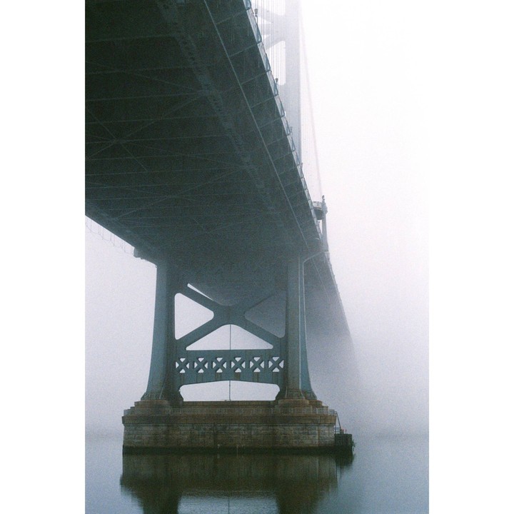 The Benjamin Franklin Bridge is seen from below, partially obscured by fog.