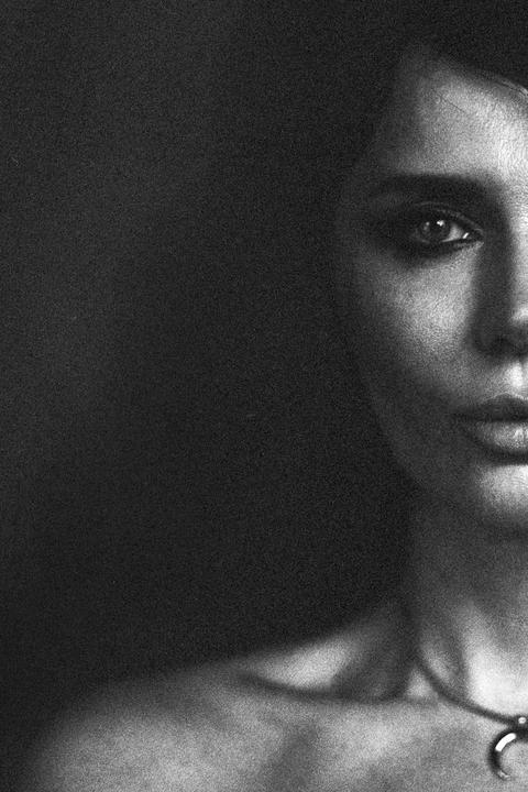 A woman's face is partially visible in a black and white portrait, with her eye and lips in focus.