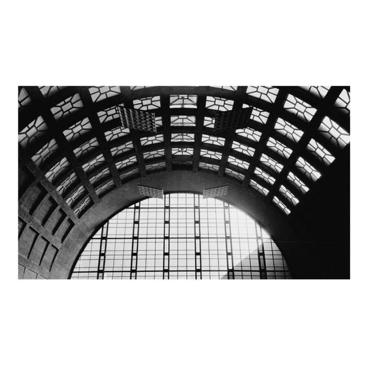A large arched window with a grid pattern is visible under a vaulted ceiling with geometric cutouts.