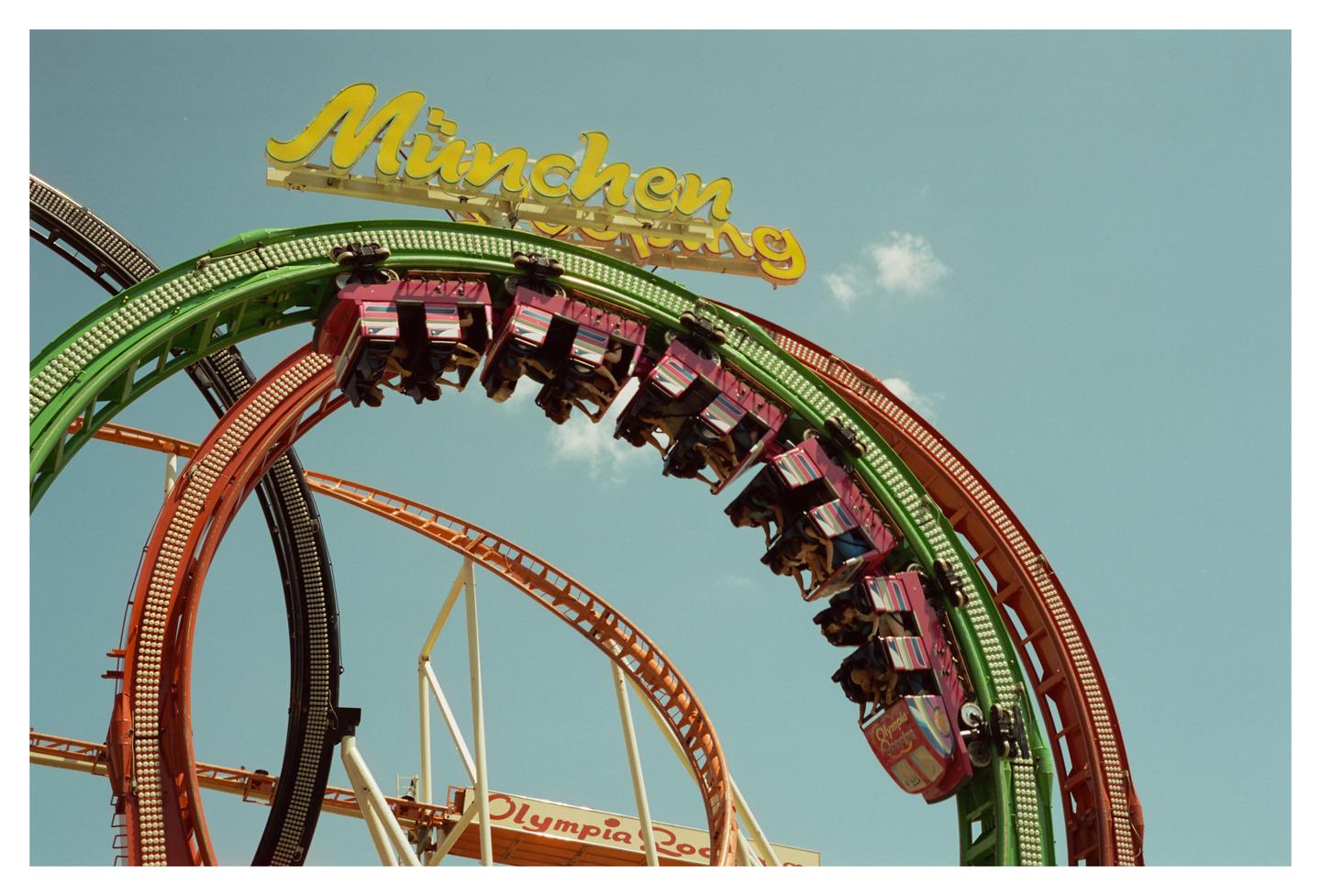 A roller coaster with people in its cars is looping upside down against a clear blue sky.