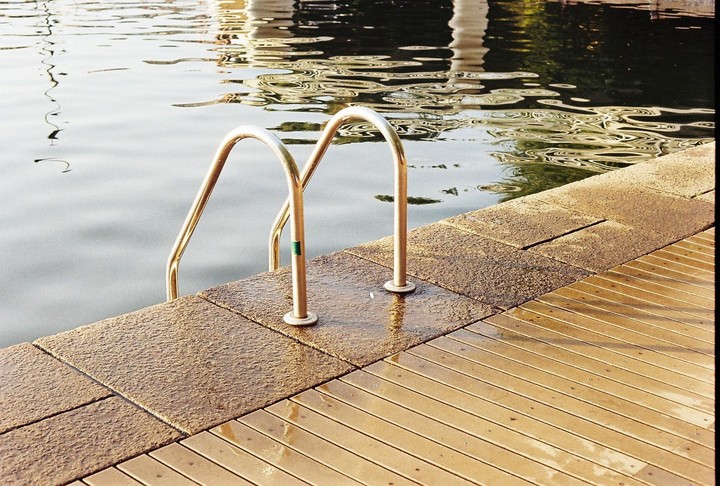 A metal ladder extends into the water from a wooden and stone dock.