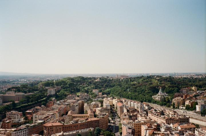 A panoramic view shows a city with many buildings and a large green area with trees.