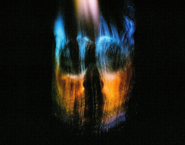 Abstract light streaks of blue and orange appear against a dark background.