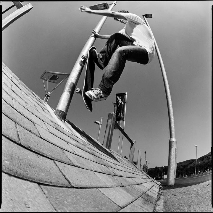 A man on a skateboard grinds a metal pole next to a tiled wall.