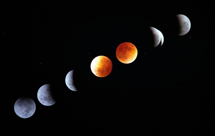 A composite image shows the moon in various phases of a lunar eclipse against a dark sky with stars.
