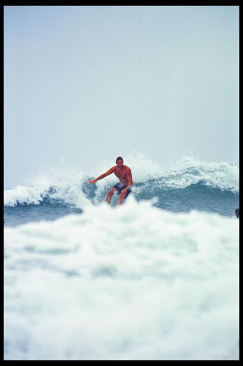 A man surfs a wave under an overcast sky.
