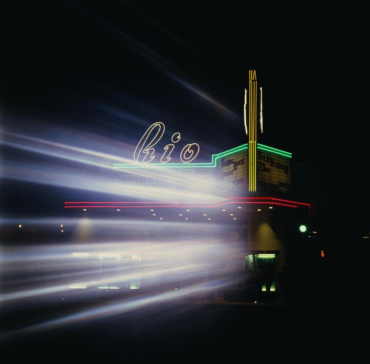 A building with neon signs is illuminated at night with light streaks across the frame.