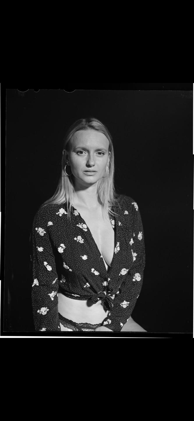 A woman with long hair and hoop earrings wears a floral top and lace underwear.
