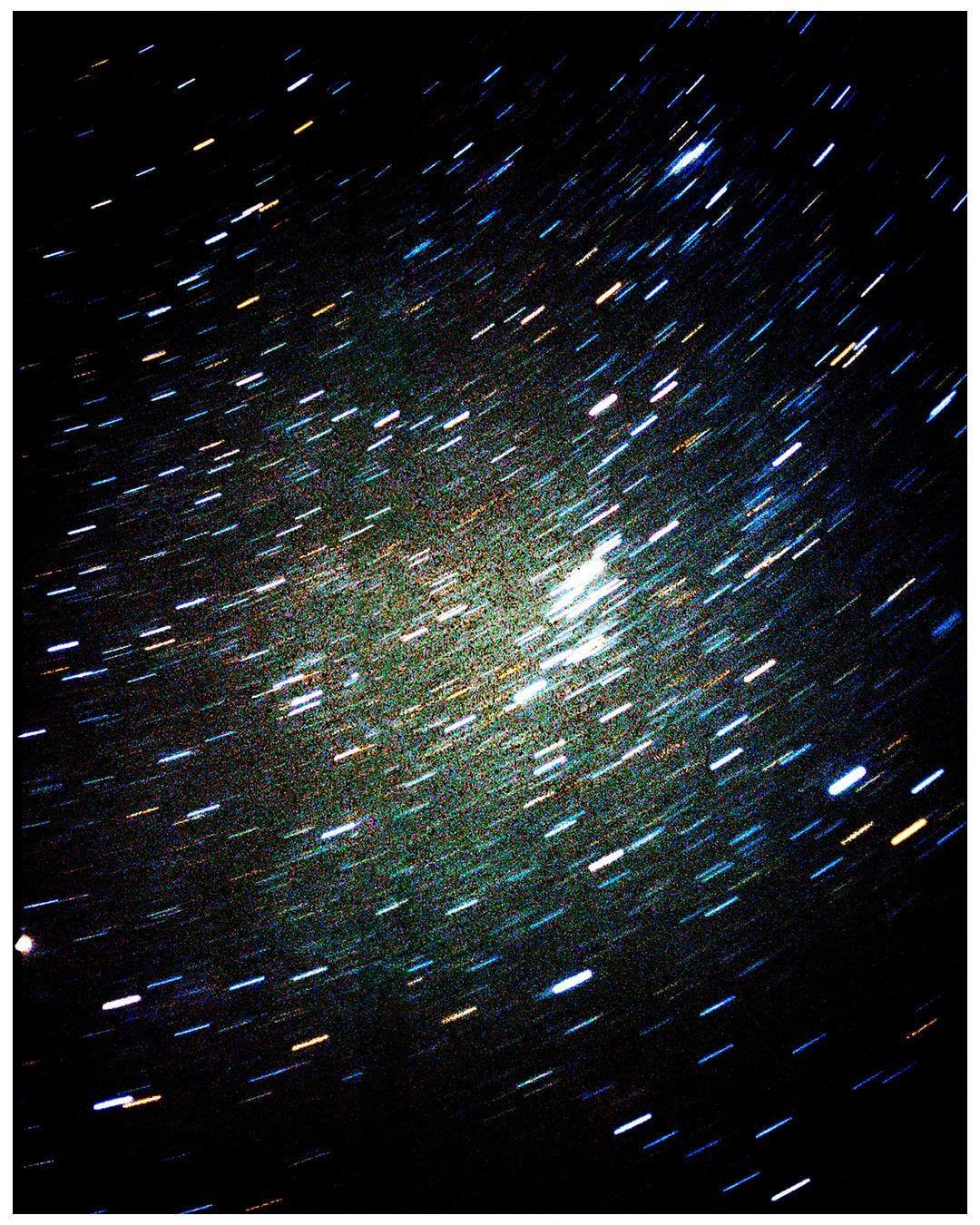 A long exposure photograph captures the movement of stars across the night sky, creating star trails.