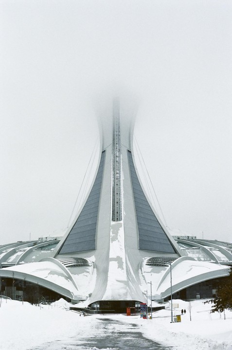 A snow-covered Olympic Stadium in Montreal is partially obscured by fog.
