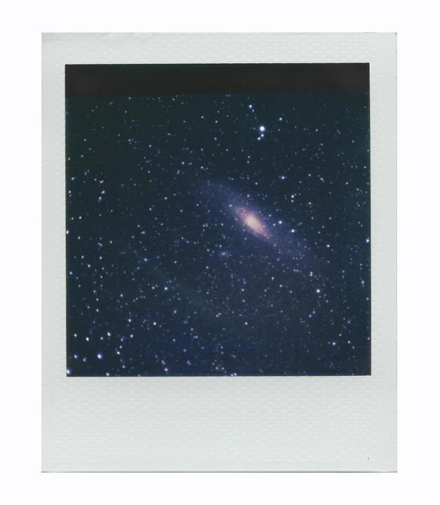 The Andromeda Galaxy is visible in a dark sky filled with many stars.