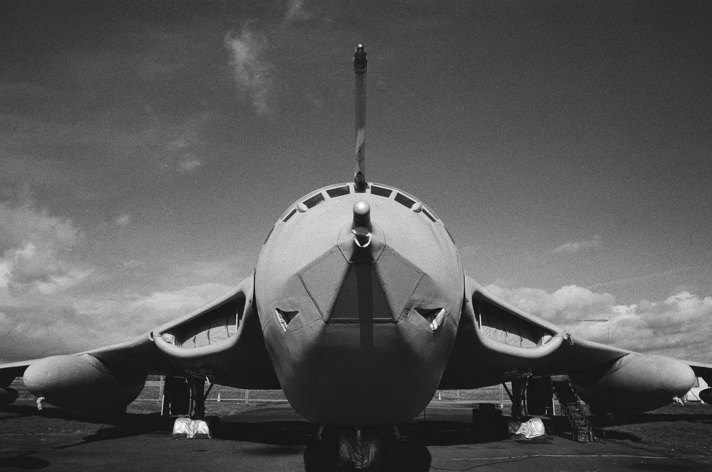 A large bomber aircraft is viewed head-on from a low angle against a cloudy sky.