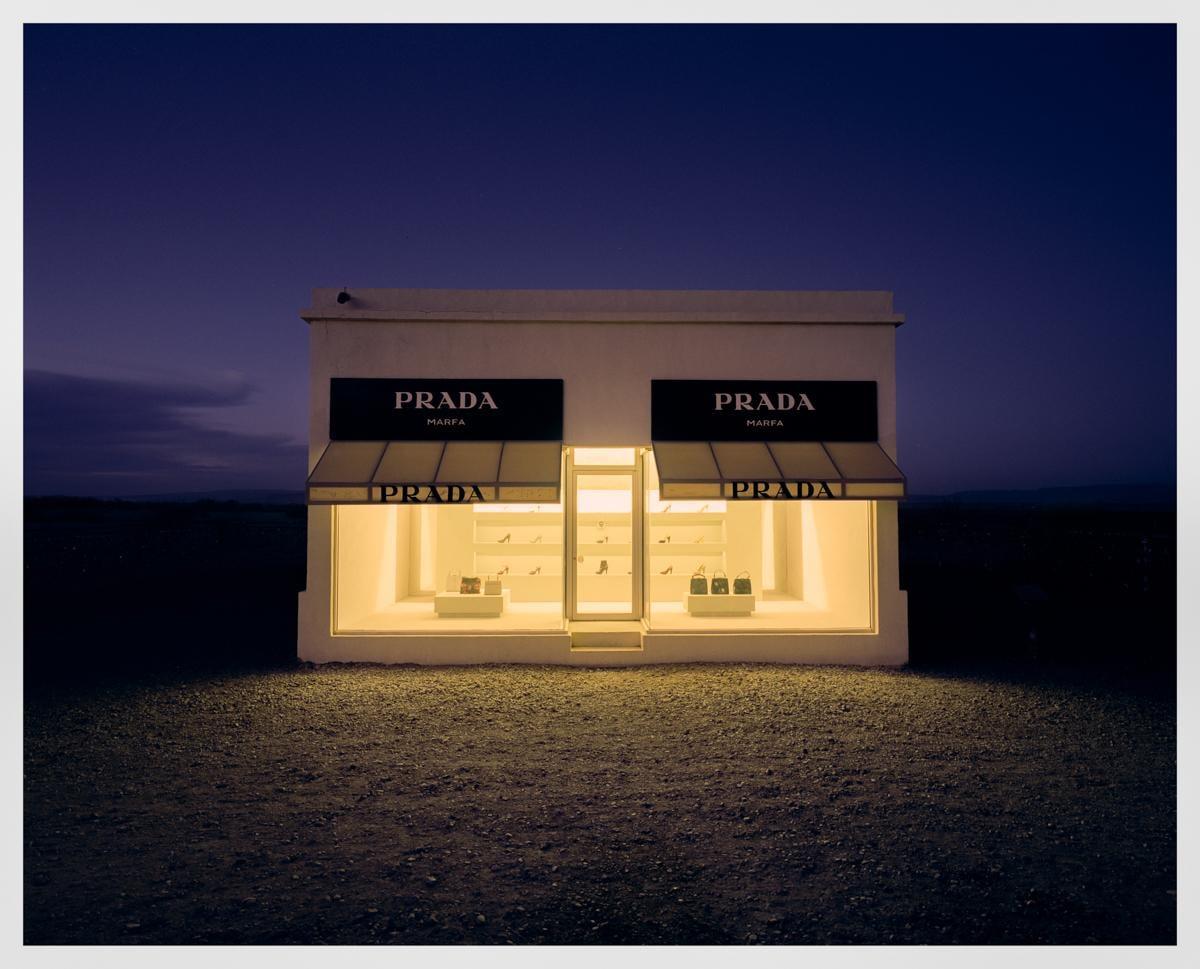 A Prada Marfa art installation is illuminated at night in a desert landscape.
