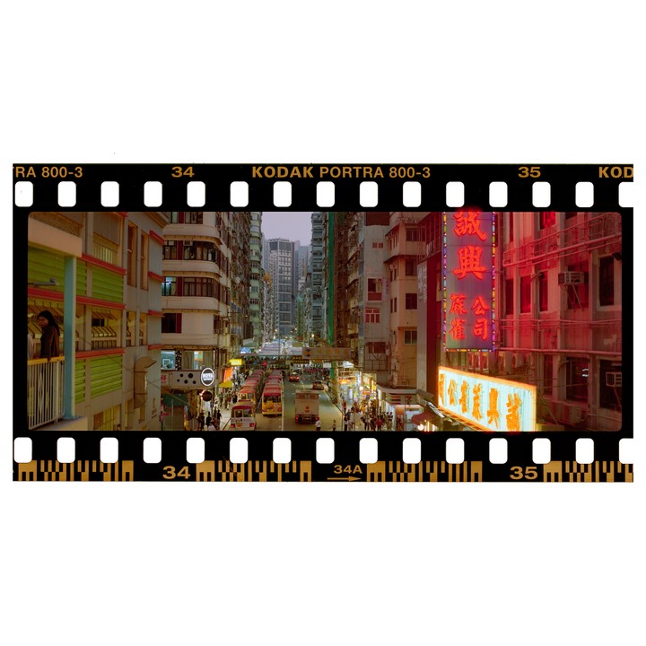 A busy street in Hong Kong is filled with buses, pedestrians, and neon signs at dusk.